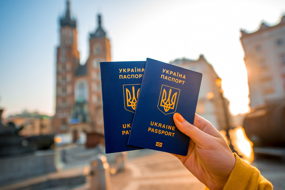 Female hands holding Ukrainian abroad passports on the Krakow city center background