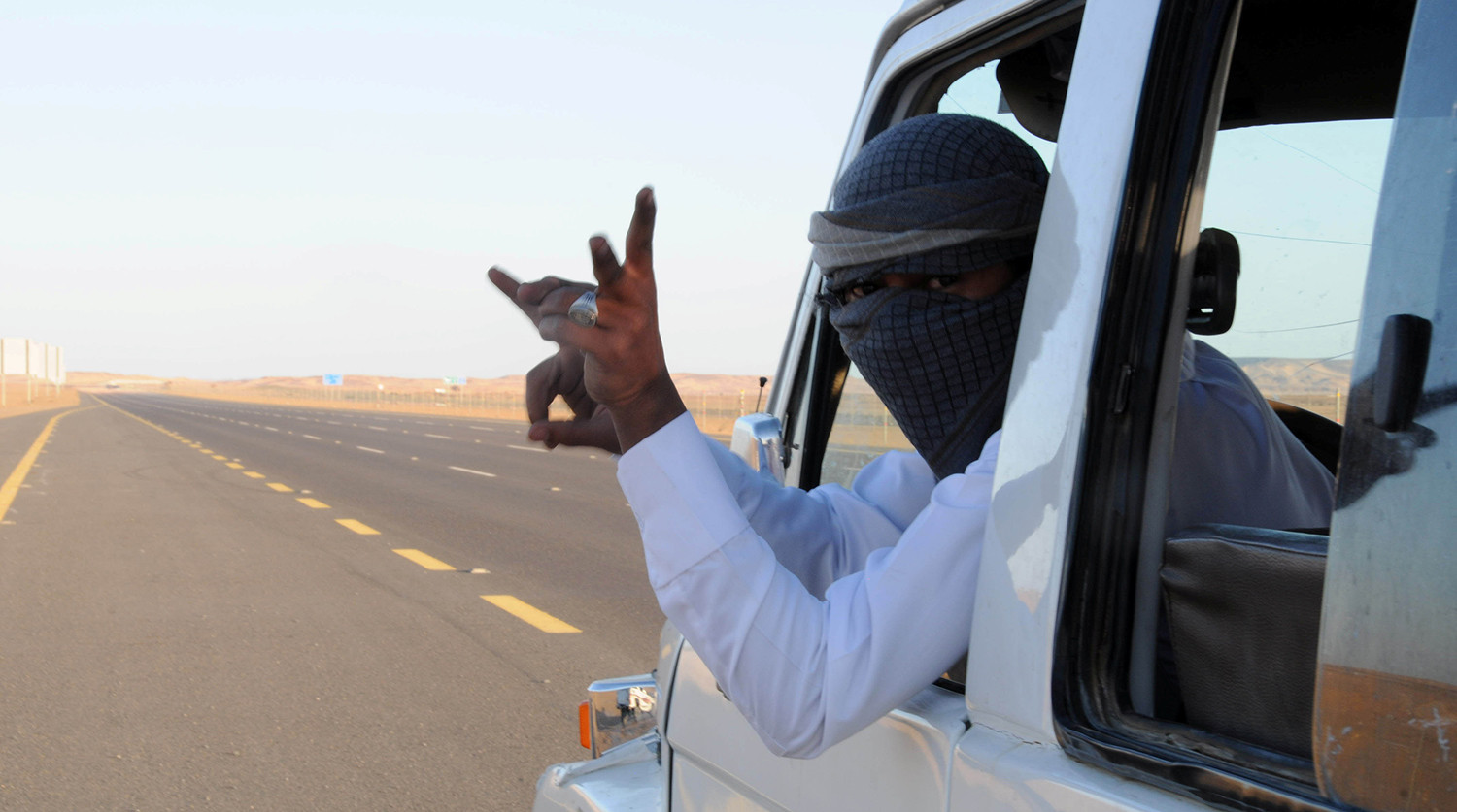 Saudi man who performs a stunt known as "sidewall skiing" gestures from his vehicle in Tabuk